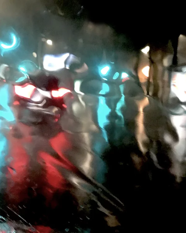 Photographie d’art impressionniste en tirage limité, une rue la nuit et une voiture qui passe nimbée de lumières colorées sous la pluie dans une rue de Paris - Sophie Moisan