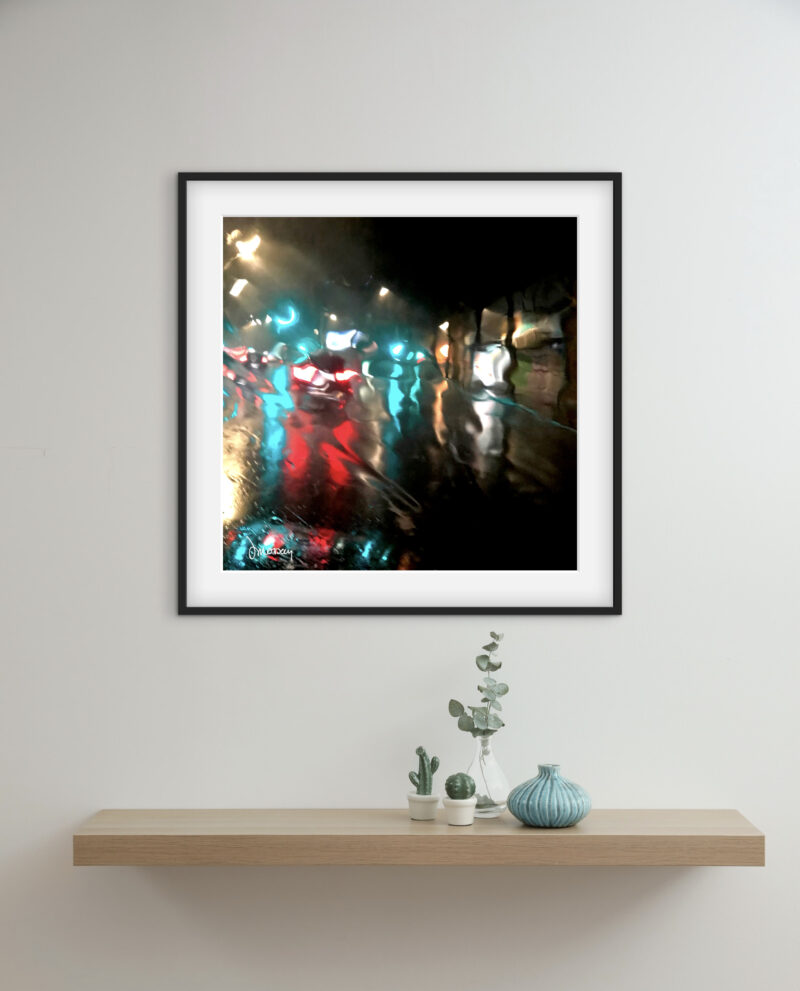 Mise en situation d'une photographie d’art impressionniste dans un salon. Tirage limité, une rue la nuit et une voiture qui passe nimbée de lumières colorées sous la pluie dans une rue de Paris - Sophie Moisan