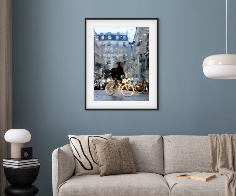 Mise en situation d'une photographie d’art impressionniste de Sophie Moisan dans un salon moderne. Tirage limité, un vélo heureux sous la pluie et couché de soleil - Sophie Moisan