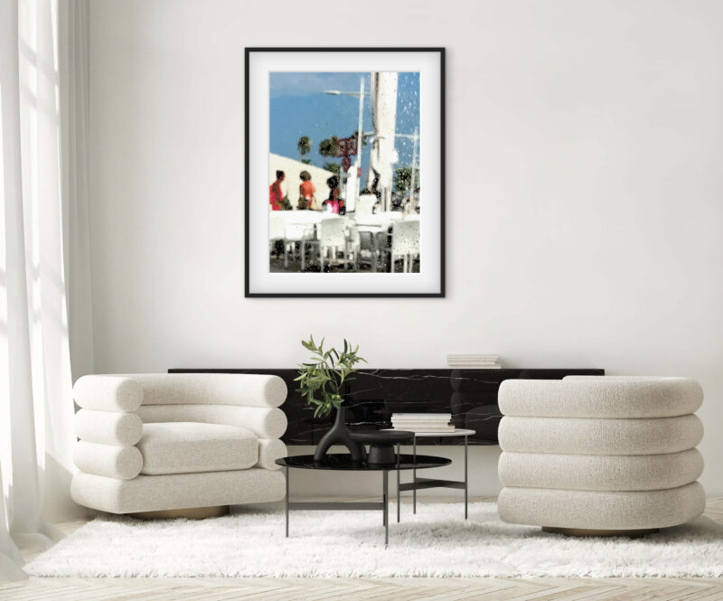 Mise en situation d'une photographie d’art de Sophie Moisan dans un salon moderne. Tirage limité, silhouettes floues habillées de rouge dans un décor épuré, sous le ciel bleu de la Riviera française. — Sophie Moisan