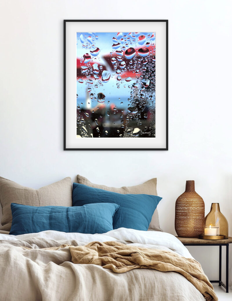 Mise en situation d'une photographie impressionniste de Sophie Moisan dans un salon moderne. Tirage limité, parasols rouges flous sur fond de ciel et mer bleue, sur un mur - Sophie Moisan